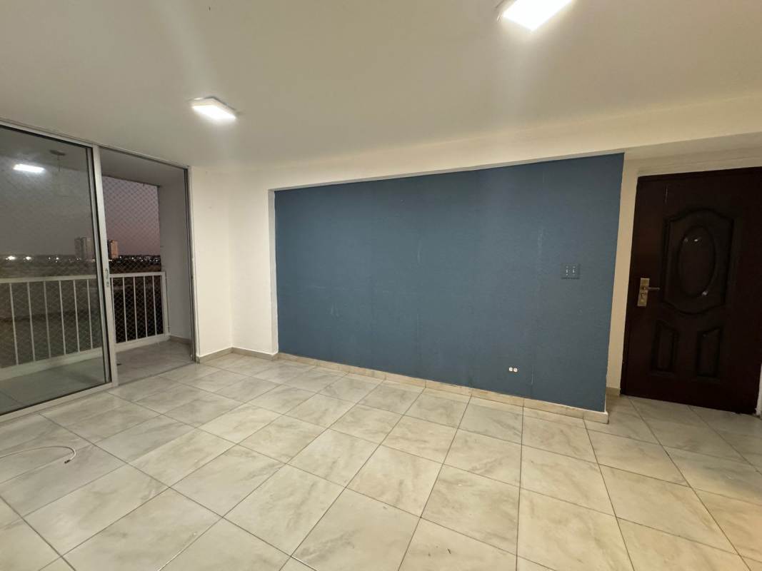 Living room with blue accent wall, sliding doors to balcony, ceramic floors in PH Mystic Blue Panama