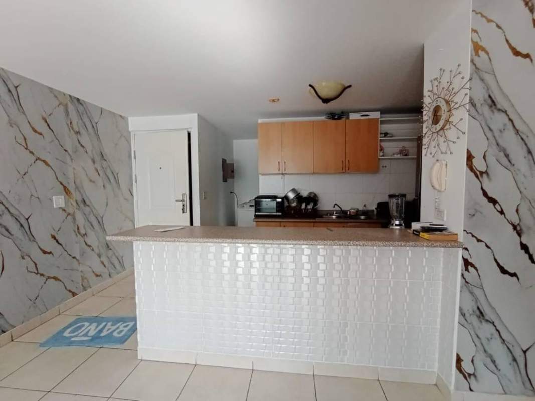 Living dining space with marble wall, ceiling fan, TV, dining table, and sliding door in PH Central Park.