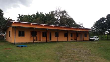 Exterior of long single-story orange building with metal roof and grassy yard in Santiago Panama