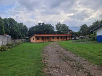 Brown building with gravel driveway and grassy yard surrounded by trees Santiago Panama