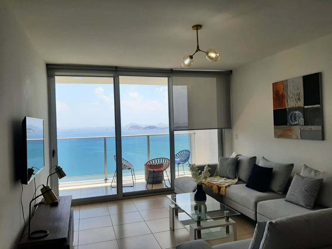 Contemporary furnished living room with panoramic ocean views and balcony access in PH BICSA Avenida Balboa Panama