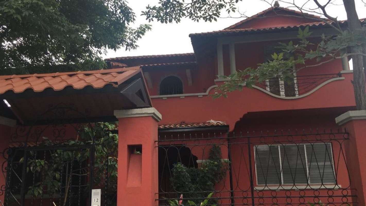 Two-story Mediterranean house red facade wrought iron gate and plants Casa Roja Bella Vista