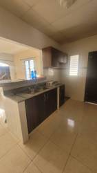 Kitchen area with beige tile flooring, dark cabinets and breakfast bar Gloria Lucrecia Chitré