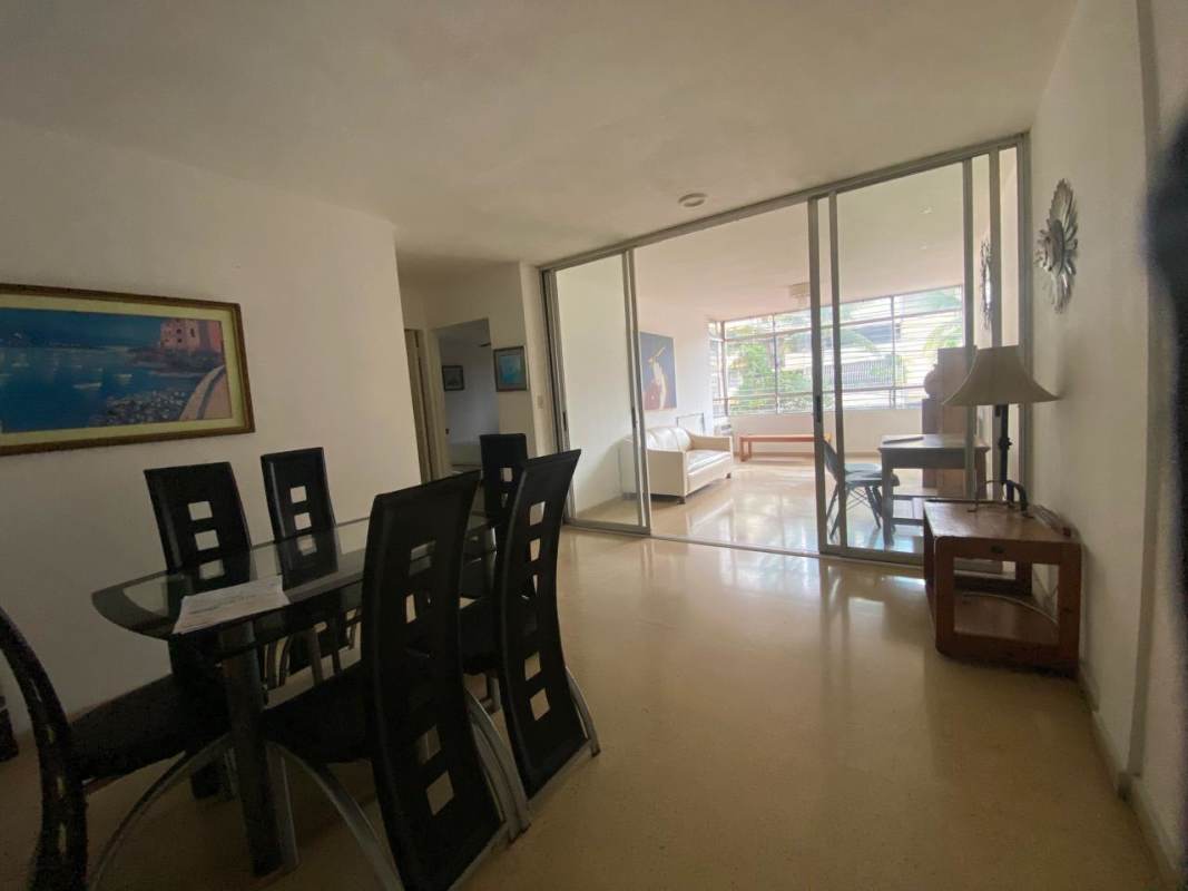 Dining area with glass table, black chairs, bright living room in PH Gobelin Panama City