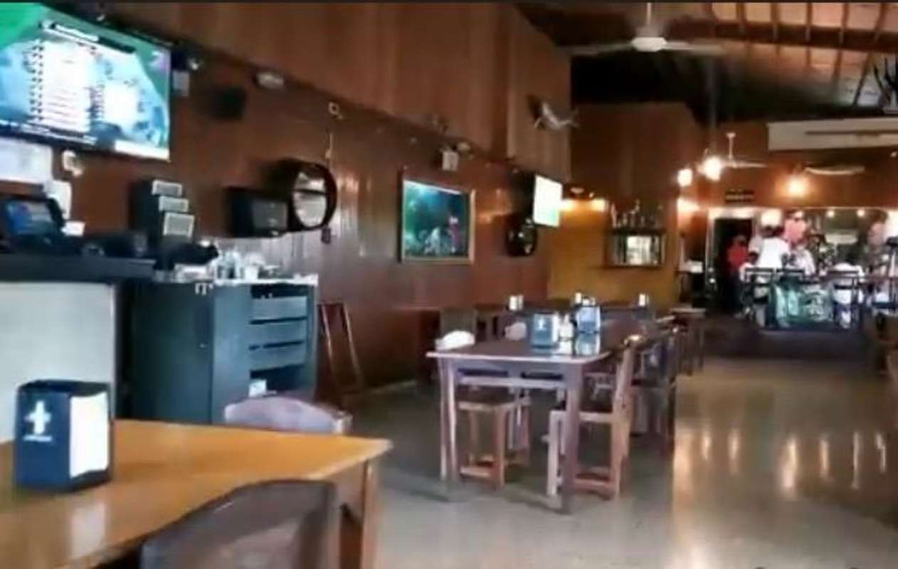 Cozy rustic restaurant interior with bar area, wood panel walls and TVs Juan Díaz Panama