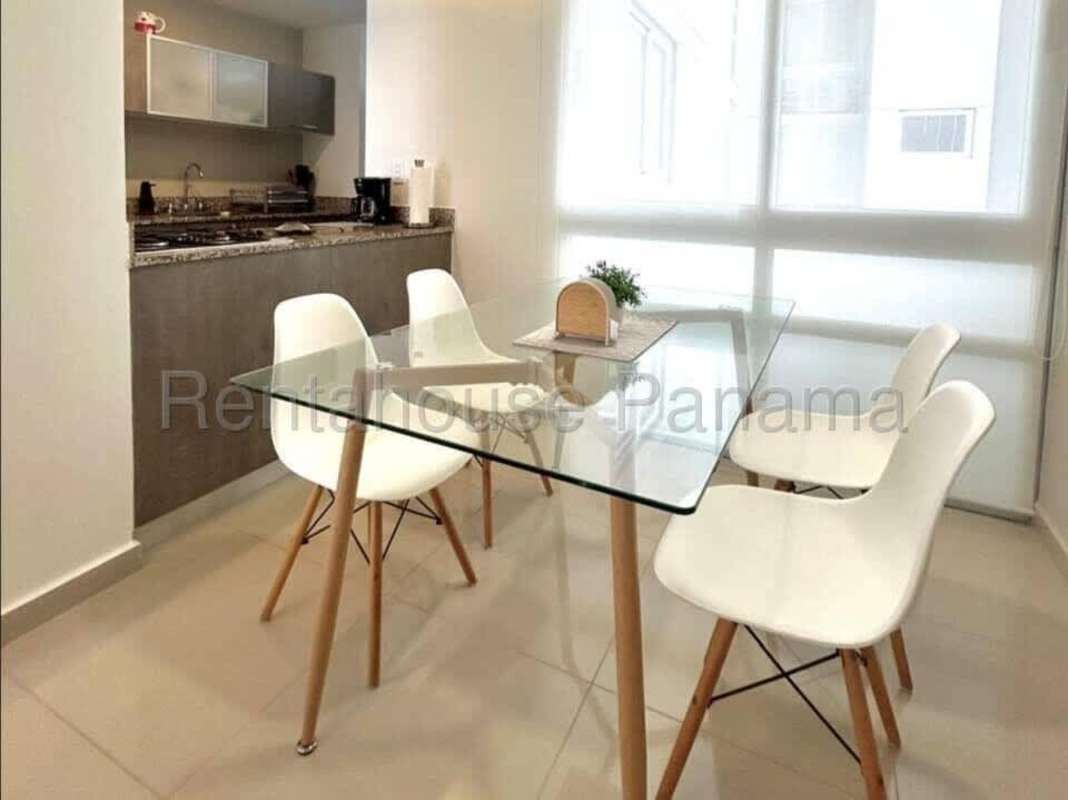 Dining room with glass table and open kitchen apartment PH Pijao Costa del Este Panama