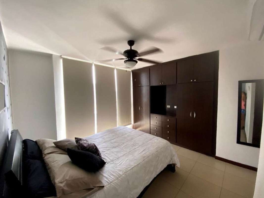 Modern bedroom with built-in wardrobe, tile floors, ceiling fan in PH Metric Panama City