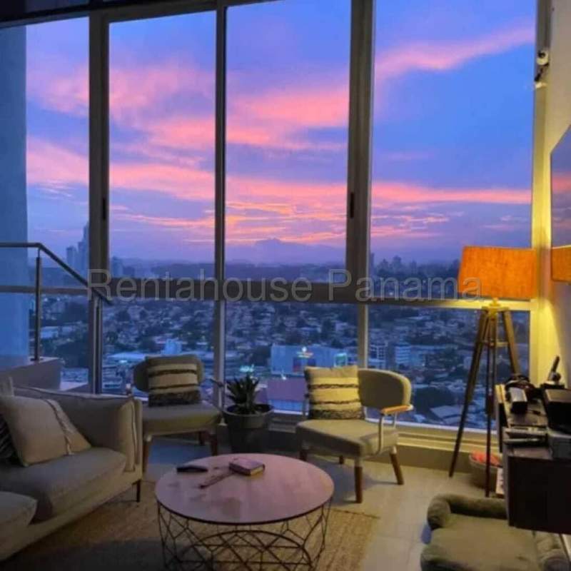 Modern living room in loft apartment with sunset skyline view floor to ceiling windows at PH Vista Loft Panama