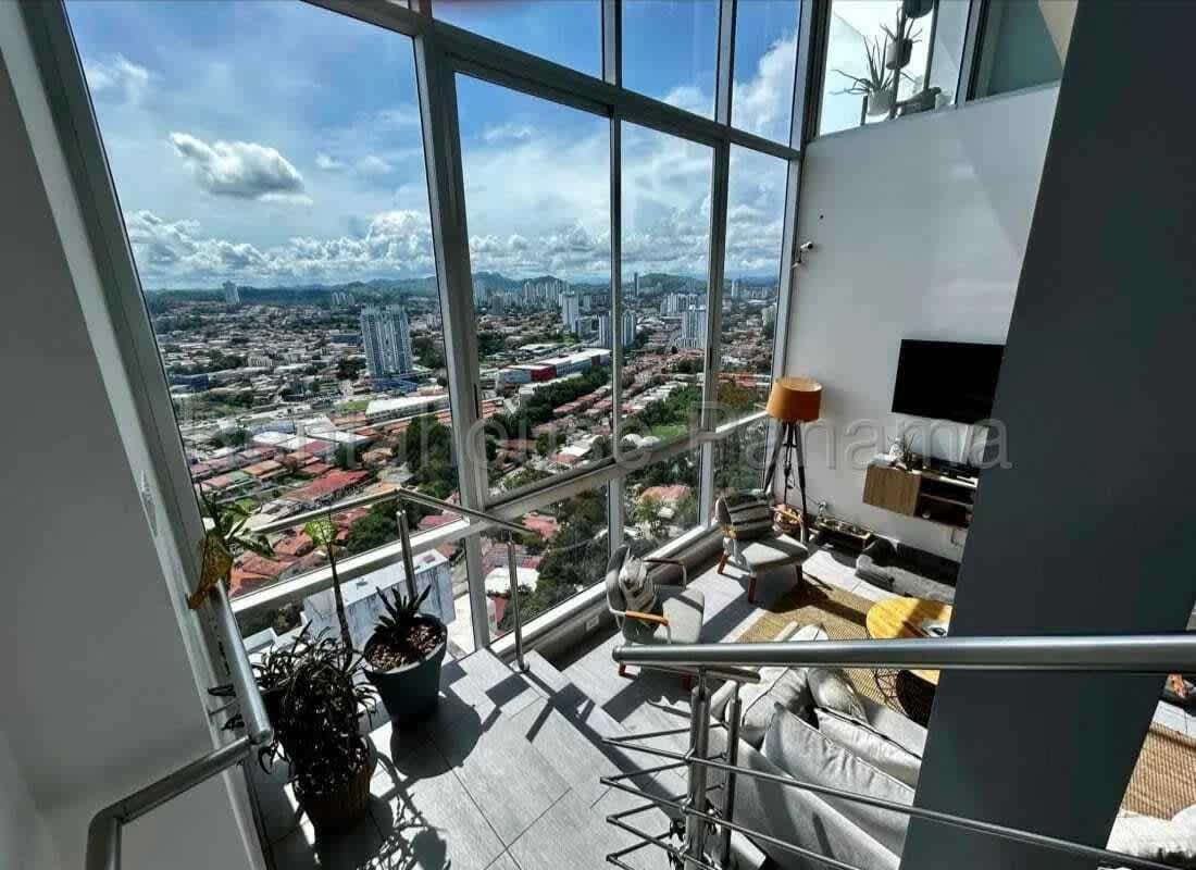 Modern loft living room space with floor to ceiling windows access to city view balcony Panama City