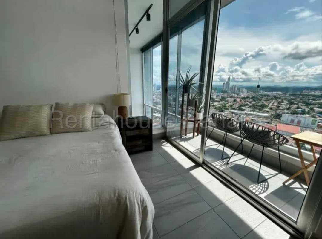 Bedroom in loft apartment with floor-to-ceiling window and balcony city skyline view at PH Vista Loft Panama
