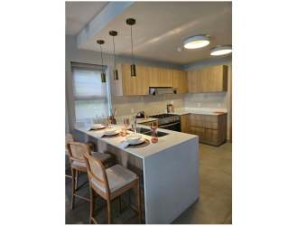 Modern kitchen with light wood cabinets, island seating, stainless appliances in new Alere Panama Pacifico home