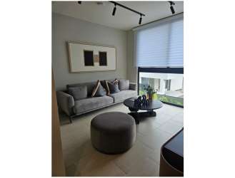 Elegant living room with gray sofa, round ottoman, large windows, modern decor in Alere Panama Pacifico house