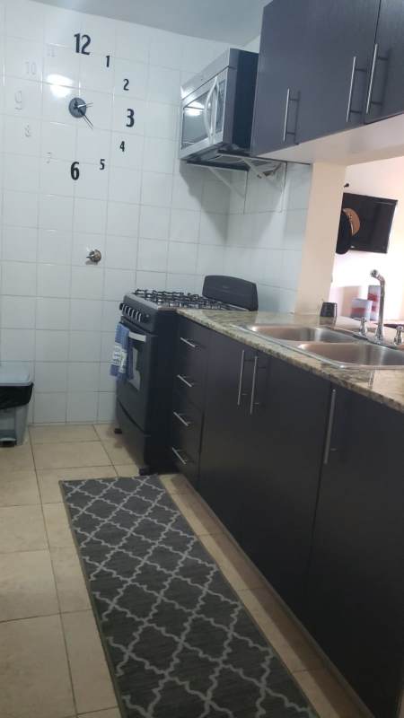 Compact kitchen with granite countertops, clock wall décor in Cosmopolitan Tower Panama apartment rental