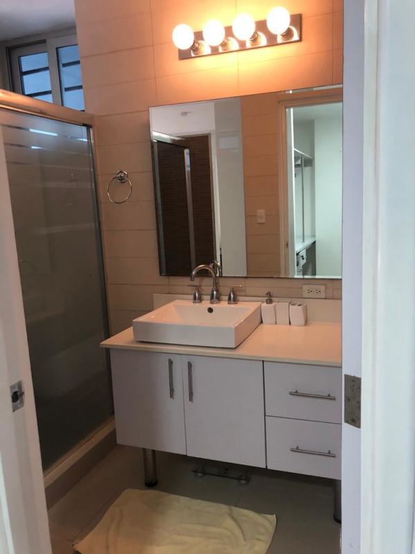 Bathroom with glass shower enclosure, white vanity, large mirror in furnished loft PH Vitro Loft El Cangrejo