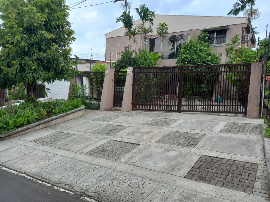 Spacious dining room with chandelier, glass block wall, red accents in Las Cumbres house Panama
