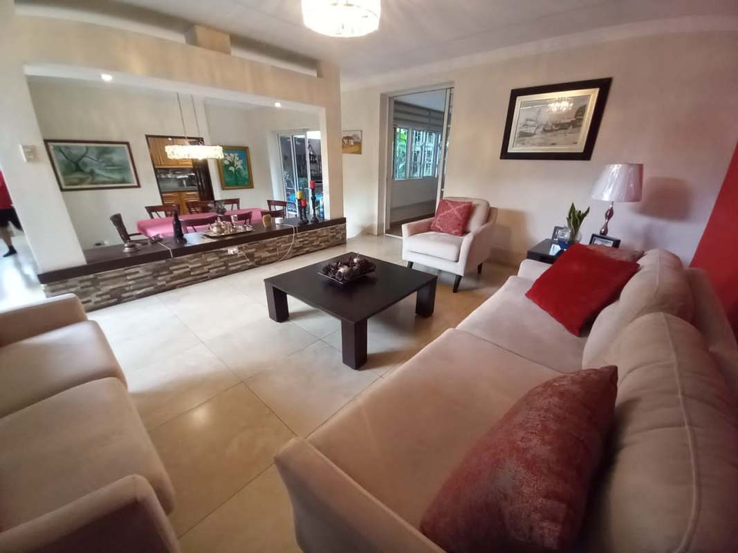 Contemporary living room with red accent wall, neutral sofas, tile floor at Las Cumbres house Panama