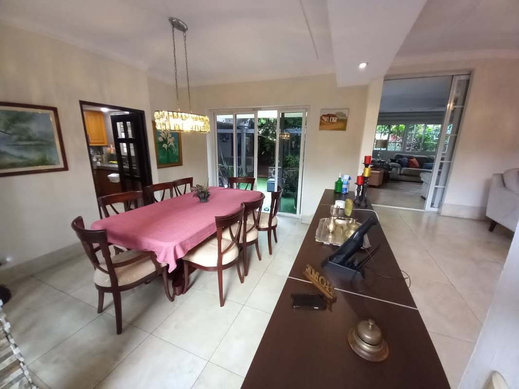 Contemporary dining room with chandeliers and garden view at Las Cumbres house Panama City