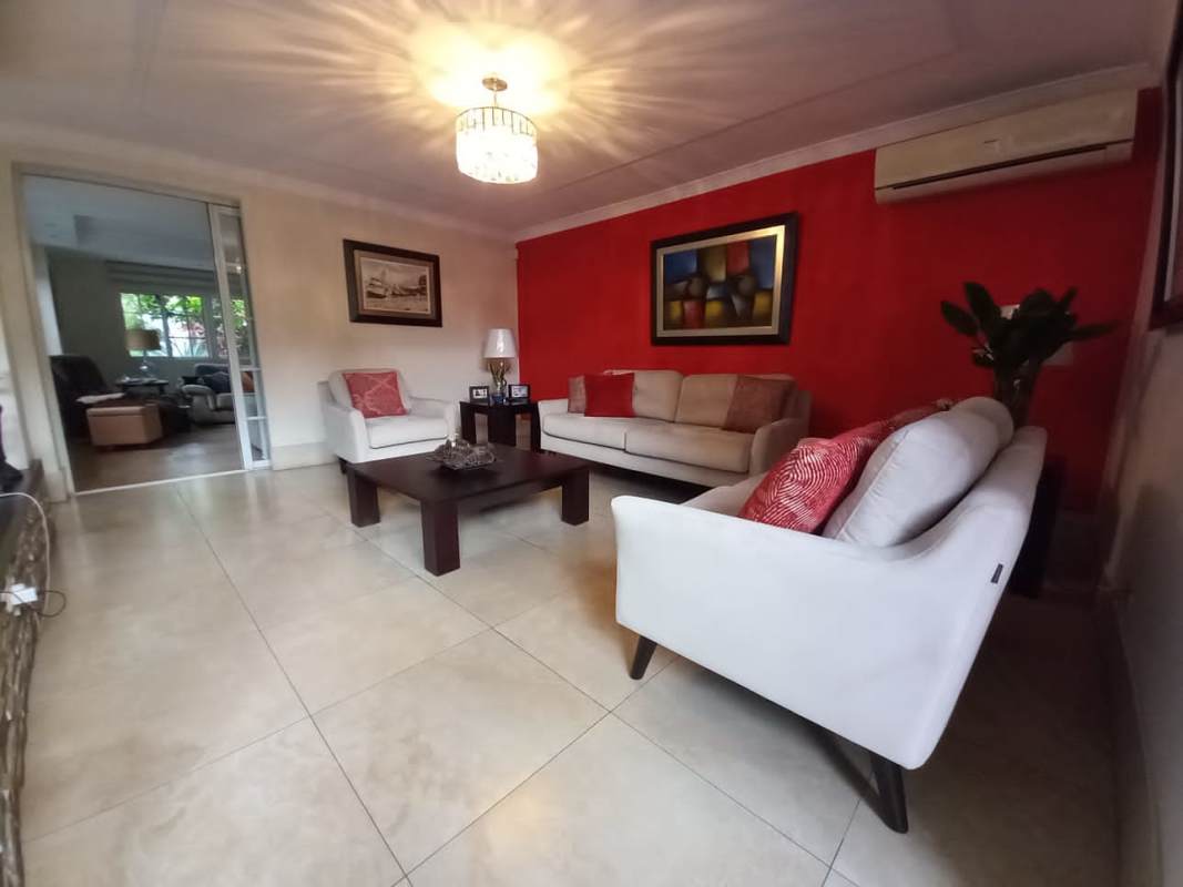 Spacious living room with ceiling fan, tile floors, flat screen TV in Las Cumbres house Panama