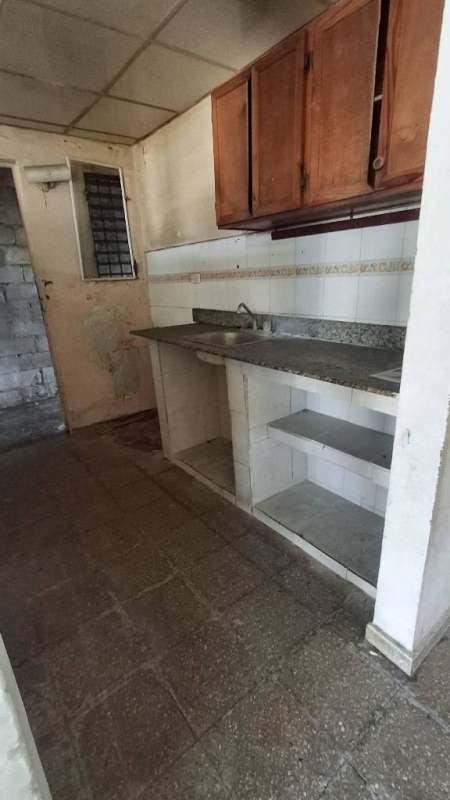 Simple kitchen with granite countertop, wood cabinets, barred window in Las Acacias Panama home