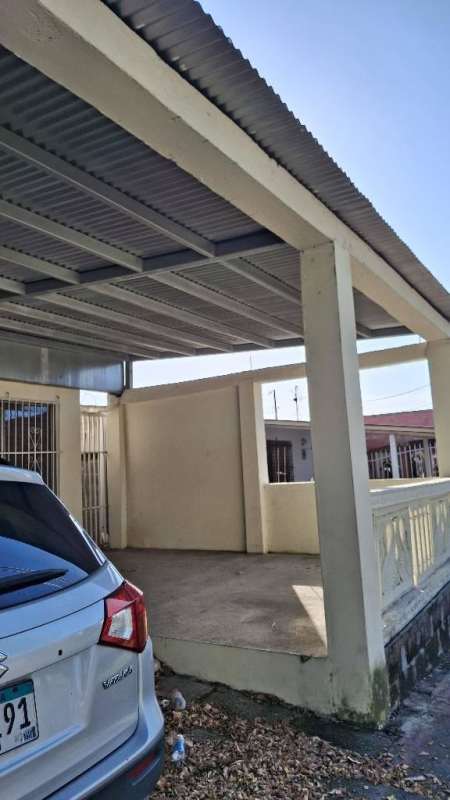 Minimalist room with concrete floor, drop ceiling and window bars in Las Acacias house Panama