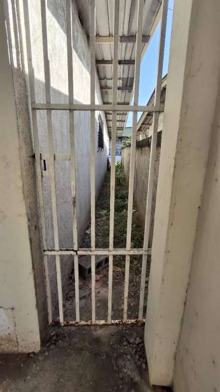 Narrow exterior walkway with metal gate and roof in Las Acacias house in Panama City