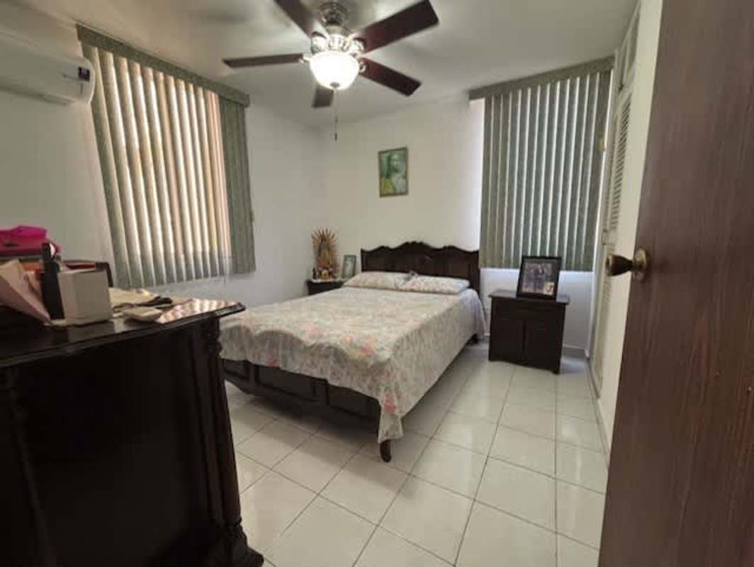 Bedroom with floral bedding, AC, ceiling fan, two windows PH La Cresta Panama
