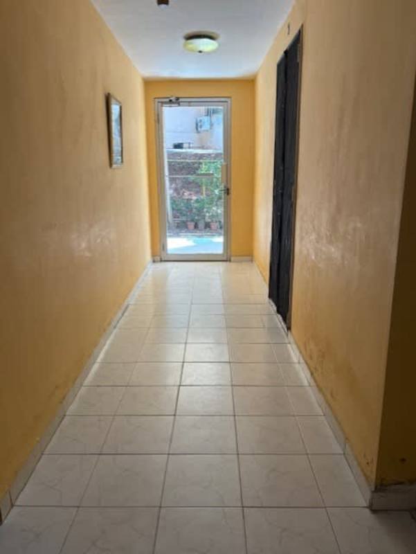 Bright hallway with yellow walls, glass exit door PH La Cresta Panama