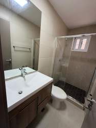 Bathroom with glass shower enclosure vanity mirror tile walls New West Costa Verde Panama