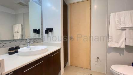 Bright open living room with sectional sofa, stone accent wall, and dining area at PH Midrise Panama Pacifico