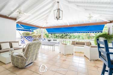 Coastal covered patio with wicker seating, hammock, blue accents in Playa Blanca oceanfront villa