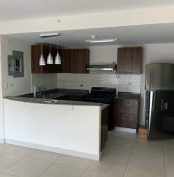 Kitchen with breakfast counter and appliances at Woodlands Midrise Panama Pacifico apartment rental