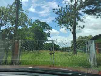 Grassy acre with partial fencing and power lines on countryside lot for sale