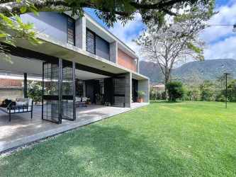 Covered outdoor dining terrace with wooden table garden view in El Valle mountain home Panama