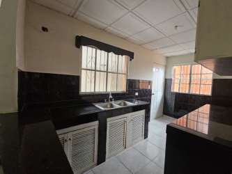 Kitchen with tile counters, double sink, modular cabinets and barred window in Brisas de Arraiján Panama