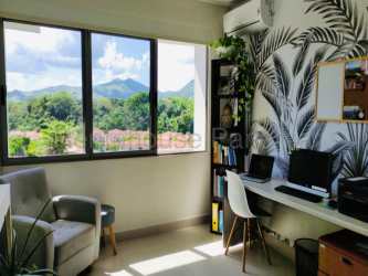 Home office space with large window, botanical wallpaper and mountain view in Woodlands apartment Panama