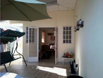 Covered tiled terrace with patio furniture and garden view in house Chitré Panama