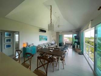 Living dining area with vaulted ceiling and ocean view balcony in Bijao condo