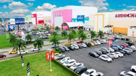 Large colorful shopping mall with parking area and palm trees under Panama's sun at Westland Mall