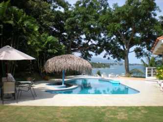Living room overlooking lush garden and pool at Punta Barco beachfront home Panama