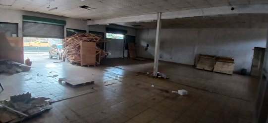 Open plan commercial warehouse interior with tiled flooring and partitioned office