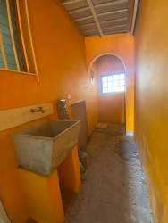 Utility room with orange walls, concrete wash sink, window bars in Valle San Bernardino Arraiján home