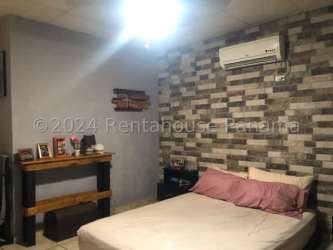 Bedroom with accent wall, air conditioning unit, bed and tile floors in Panama house for sale