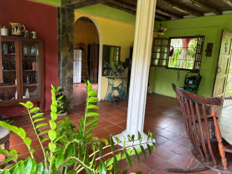 Rustic living room with wooden ceiling beams, terra cotta tiles, colorful walls, and garden view in Bique