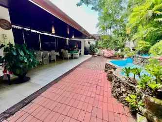Outdoor living terrace with dining area next to pool and lush green garden in Rio Hato house Panama