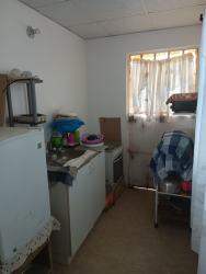 Simple small kitchen with refrigerator stove and basic amenities in Los Guayacanes home Chorrera Panama