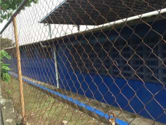 Exterior blue building with metal roof behind chain-link fence in fenced lot El Coco La Chorrera Panama