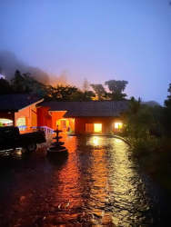 Rustic mountain living room with stone accent walls, fireplace, wood ceiling beams and large windows in Altos del María Panama