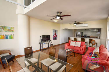 Spacious living dining area with red sofas, large windows overlooking ocean at beachfront Miramar Loft Farallón Panama