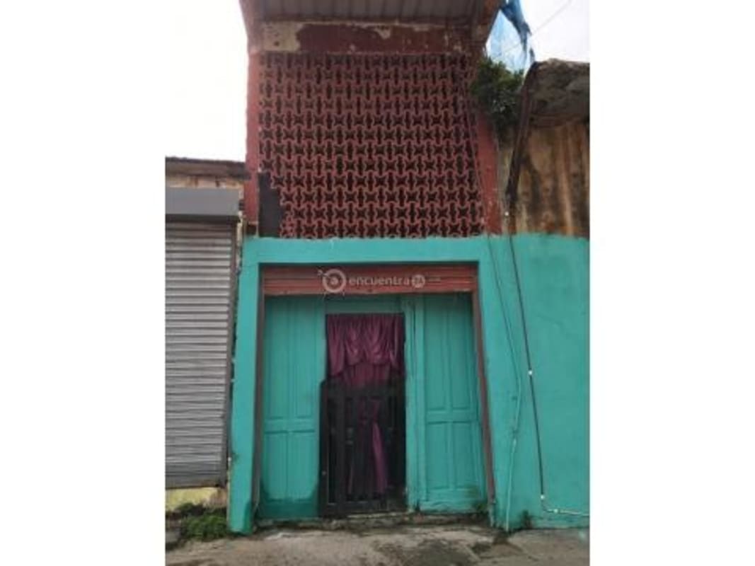 Front of two-story small building with turquoise wall, ventilated brick and metal entry gate in Casco Viejo Panama