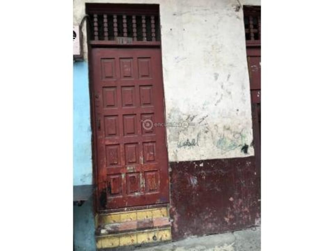 Small colonial building with metal rolling shutter, turquoise facade, brickwork above, situated in Casco Viejo